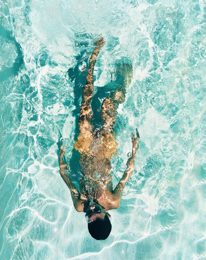 Young man relaxing in the turquoise waters of his swimming pool