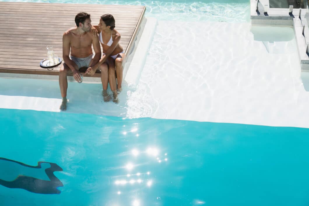 Young couple relaxing by a sunny swimming pool